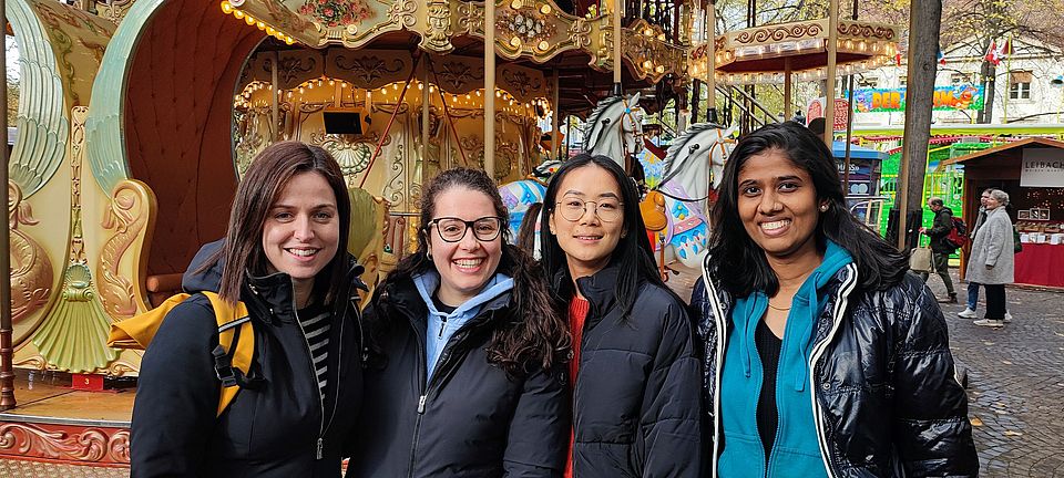 A picture of our new group members with a carussel in the back. From left to right: Giulia, Chiara, Minqi and Athira.