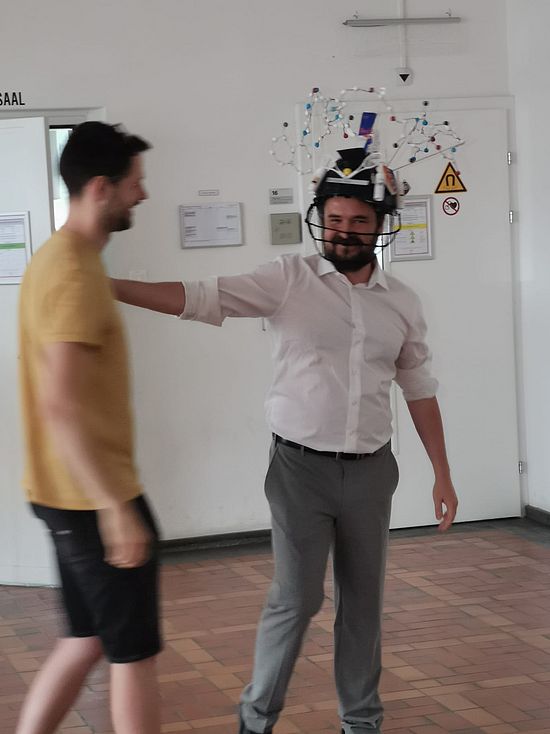 Dr Caspar Vogel wearing his hat after his successful oral examination. The hat looks like a football helmet dyed in the colors of the Seahawks.